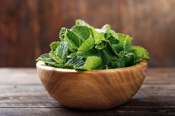 Fresh mint in a wooden plate on a wooden background.