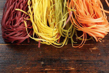 multicolored pasta on wooden background