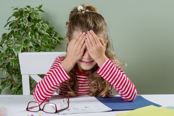 Cute junior schoolgirl with blond hair, smiling, drawing in a sc