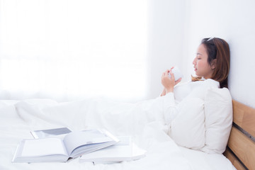 Asian woman with cup of coffee in bedroom with morning.