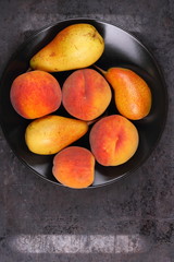 Pears and peaches on a black plate in retro style for a designer on a metal old background