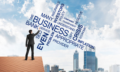 Young businessman standing on house roof and writing leadership skill concept. Mixed media