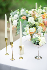 decorated wedding table with beautiful flower composition, candles and glass, outdoor, fine art.