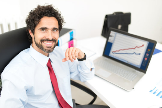 Happy businessman in front of his laptop computer