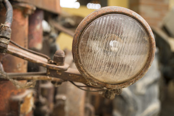Fototapeta na wymiar Old rusty headlight of a broken and abandoned farm tractor