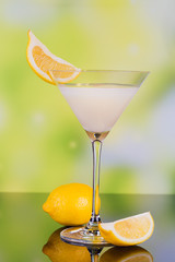 Glasses of cream liqueur with lime and lemon on green background with reflection.