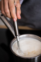 Female cook mixing ground corn grains into the boiling water in preparation of the polenta meal