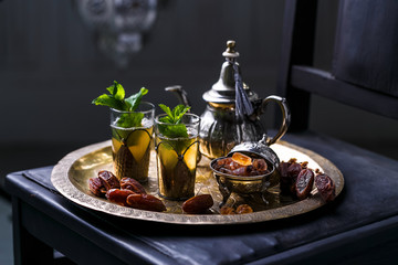 Moroccan mint tea in the traditional glasses on a tray and kettle