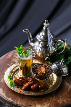 Glass of mint tea with dates and sugar, on copper plate