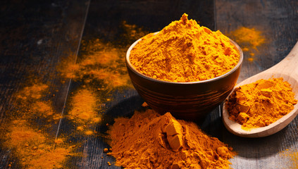 Composition with bowl of turmeric powder on wooden table - obrazy, fototapety, plakaty