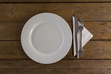 White plate with cutlery and napkin on table