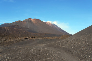 Fototapeta na wymiar Moon-like landscape of Mount Etna with smoke from the crater, Sicily, Italy
