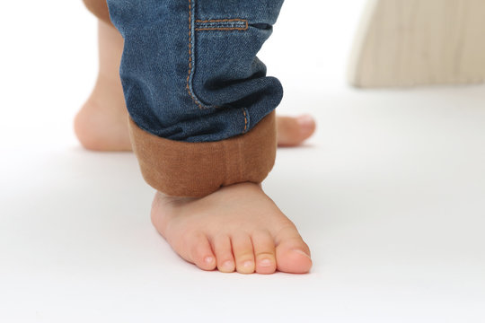 close-up on the feet of a baby standing and wearing jeans
