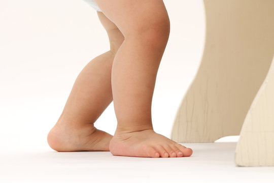 close-up on the legs and feet of a baby standing with his diaper
