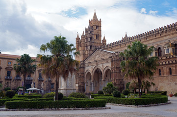 Fototapeta na wymiar Palermo Cathedral surrounded by palms of green square, Sicily, Italy