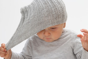 child who does not want to wear a bonnet on his head