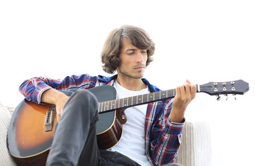 Handsome man playing on the guitar on the couch at home