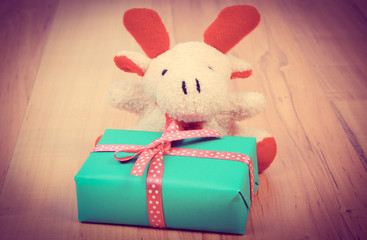 Fototapeta premium Vintage photo, Plush reindeer with gift for Christmas or other celebration