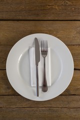 White plate with cutlery and napkin on table