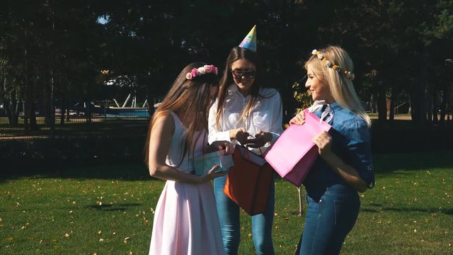 Birthday girl receives congratulations and gifts from girlfriends. All are elegantly dressed and joyful. Cheerful birthday party.