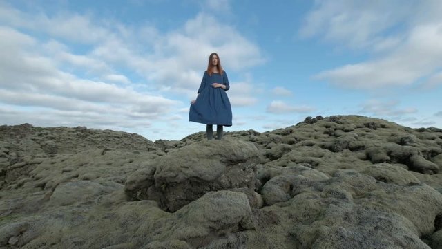 Young summer beauty. Red haired girl in blue dress on Green mossy icelandic landscape