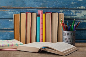 Stack of books, open book and pen holder