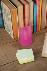 Fototapeta na wymiar Stack of books, chemical beaker and sticky notes