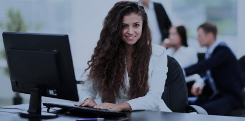 Happy young businesswoman looking behind and her colleagues work