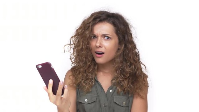 young curly woman surprising with negative answer over mobile phone expressing irritation disappointment isolated on white background. Concept of emotions