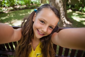 Portrait of playful girl sitting on bench