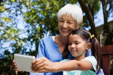 Smiling grandmother and granddaughter taking selfie while