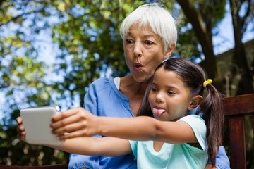 Grandmother and granddaughter making face while taking selfie