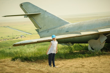 Little girl in a baseball cap at the airport near the old military aircraft.