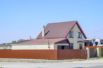 House with plastic windows and roof of corrugated sheet. Roofing of metal profile wavy shape on the house with plastic windows