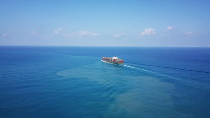 Huge large mega container ship sails on open water fully loaded with containers and cargo - aerial view