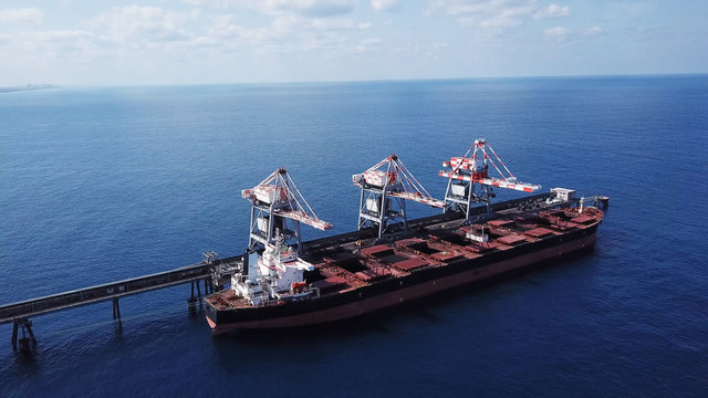 Large bulk carrier ship docking - Unloading coal ship by cranes on the power station dock