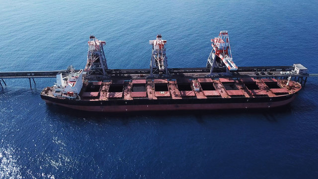 Large bulk carrier ship docking - Unloading coal ship by cranes on the power station dock