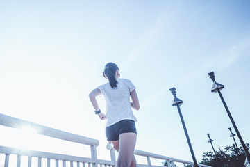 Healthy woman doing exercises and warm up before running and jogging on bridge at morning 