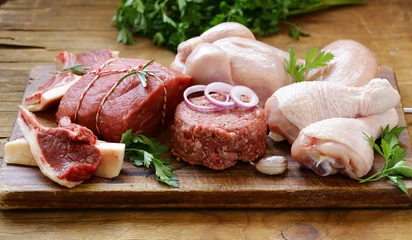 Crédence de cuisine en verre imprimé Viande assortiment de viandes crues - boeuf, agneau, poulet sur une planche de bois