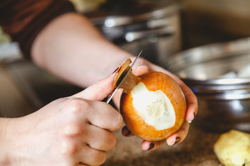 Cleaning  onions. woman hands clean bulb with knife closeup