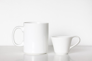 Two white porcelain mugs, different size and design, Big tea and small coffee cups, clean dishes mock up