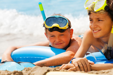 Boy in scuba mask on the sea beach with a friend