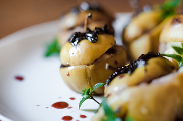 Baked apples in the oven and cartoon. Autumn dish on a white plate. Fragrant apples with cottage cheese, nuts, mint and chocolate.