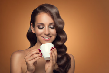 Portrait of beautiful woman drinking coffee on brown background.