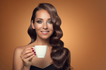 Portrait of beautiful woman drinking coffee on brown background.
