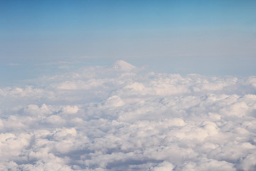 Fototapeta premium Clouds on sky and the Fuji peak above the airspace of Japan photo from airplane window