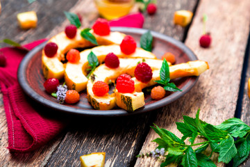 Grilled pumpkin with honey, raspberry and mint on wooden rustic background. Close up.
