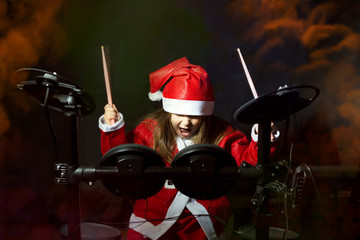 Little drummer disguised as Santa Claus playing the electronic drum kit