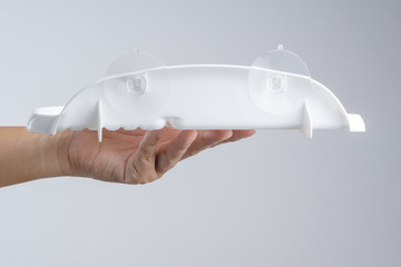 Hand holding plastic shelf with transparent suction cup for using in toilet or kitchen