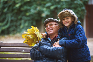 Grandson with grandfather on a walk in the autumn Park . Family values